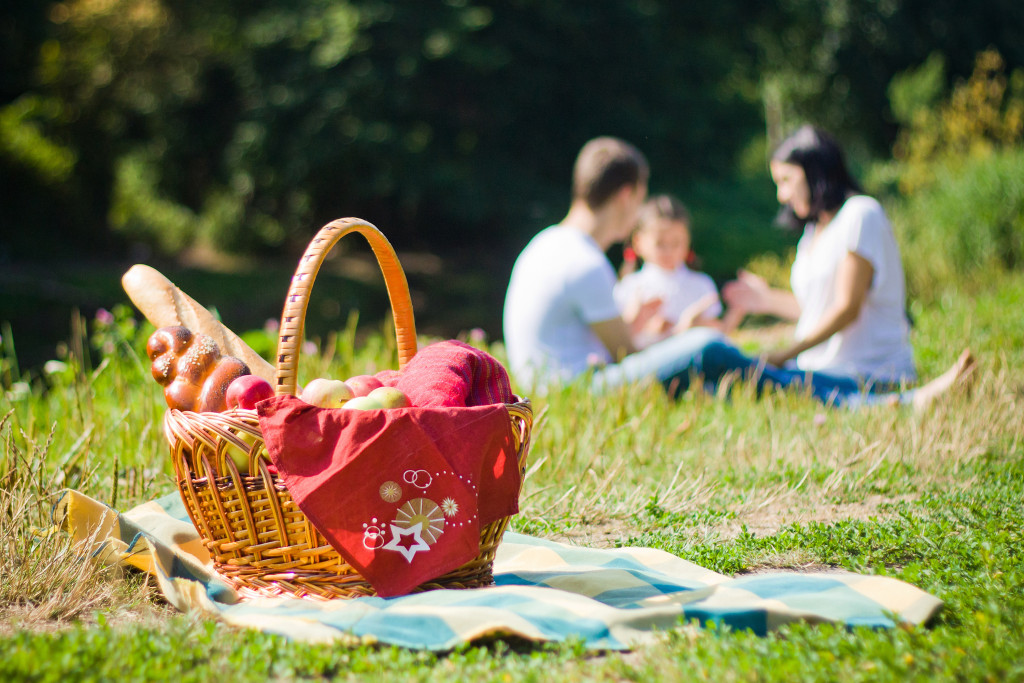 family having picnic in a park with basket in foreground