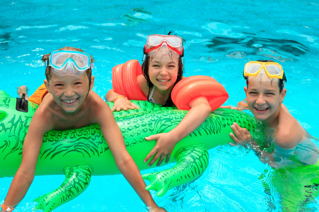 kids swimming in a pool with large inflatable crocodile