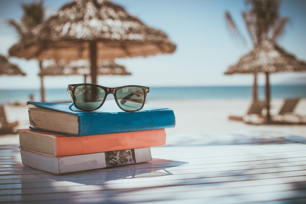 A stack of books and eyeglasses on the beach